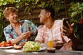 Cheerful male friends laughing while using mobile phone during barbeque party