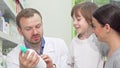 Cheerful male pharmacist helping young woman with little son