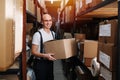 Cheerful male warehouse worker holding a box, radiantly smiling