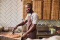 Handsome Afro American man cutting pepperoni pizza in pizzeria Royalty Free Stock Photo