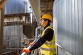 Joyful man engineer standing near metal pipe at factory Royalty Free Stock Photo