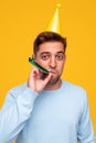 Cheerful man blowing noisemaker during party