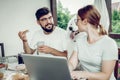 Cheerful man eating sandwich and looking at his wife