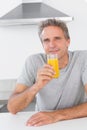 Cheerful man having glass of orange juice in kitchen Royalty Free Stock Photo