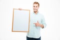 Cheerful man holding blank white board and pointing on it Royalty Free Stock Photo