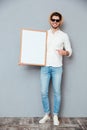 Cheerful man holding blank white board and pointing on it Royalty Free Stock Photo