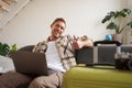 Cheerful man with laptop, tourist sits near suitcase, shows thumb up, books a holiday, goes on vacation Royalty Free Stock Photo