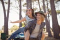 Cheerful man piggybacking woman against trees Royalty Free Stock Photo