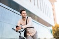 Cheerful man poses with bicycle. Young hipster with smartphone near building