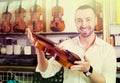 Cheerful man purchasing traditional violins Royalty Free Stock Photo