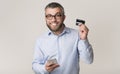 Cheerful man recommending credit card, holding cellphone Royalty Free Stock Photo