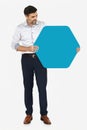 Cheerful man showing a blank blue hexagon shaped board Royalty Free Stock Photo