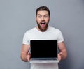 Cheerful man showing blank laptop computer screen