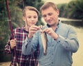 Cheerful man with son looking at fish on hook Royalty Free Stock Photo