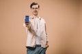 Cheerful man standing with hand in pocket and holding smartphone with facebook app on screen isolated
