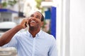 Cheerful man standing outside on street talking on mobile phone Royalty Free Stock Photo