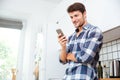 Cheerful man standing and using mobile phone on the kitchen Royalty Free Stock Photo