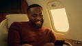 Cheerful man texting friend at plane window closeup. Happy businessman enjoying