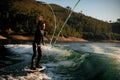 Cheerful man throws a rope and rides a wave on a foil wakeboard