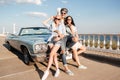 Cheerful man and two happy women standing near vintage cabriolet Royalty Free Stock Photo