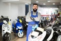 cheerful man worker displaying various motorcycles in workshop Royalty Free Stock Photo