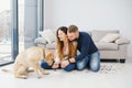 Cheerful married couple is playing with dog at home. They are sitting on sofa and stroking the animal. The man and woman are Royalty Free Stock Photo