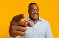 Cheerful mature African American man pointing index finger at camera on orange studio background Royalty Free Stock Photo