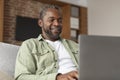 Cheerful mature black man typing on computer, has video call, enjoy communication due social distance Royalty Free Stock Photo