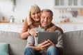 Mature Couple Using Digital Tablet Computer Sitting On Sofa Indoor Royalty Free Stock Photo