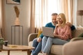 Cheerful Mature Couple Using Laptop Sitting On Sofa At Home Royalty Free Stock Photo