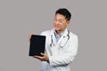 Cheerful mature korean male therapist in white coat with stethoscope shows tablet