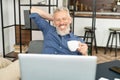 Cheerful mature male employee enjoys morning coffee at the workplace in the office