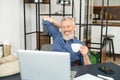 Cheerful mature male employee enjoys morning coffee at the workplace in the office