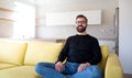 Cheerful mature man sitting on sofa in unfurnished house. Royalty Free Stock Photo