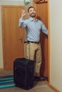 cheerful mature man with suitcase looking away while entering