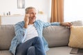 Cheerful mature man talking on cellphone sitting on couch Royalty Free Stock Photo