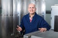 Cheerful mature man working in wine secondary fermentation section Royalty Free Stock Photo