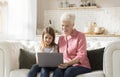 Cheerful mature woman and her granddaughter using laptop together indoors, playing video games or browsing internet Royalty Free Stock Photo