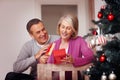 Cheerful mature woman with husband opening Christmas present. Portrait of a cheerful mature woman with husband opening Royalty Free Stock Photo