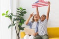 Cheerful mature woman with laptop looking kid boy holding USA flag, Grandmother and grandchildren playing cheerfully in living Royalty Free Stock Photo