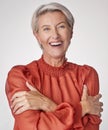 Cheerful mature woman laughing and hugging herself against a grey studio background. Happy senior woman embracing and Royalty Free Stock Photo