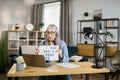 Cheerful mature woman presenting financial report to colleagues through video call on laptop. Royalty Free Stock Photo