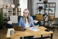 Cheerful mature woman presenting financial report to colleagues through video call on laptop. Royalty Free Stock Photo