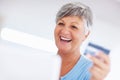 Cheerful mature woman shopping online. Cheerful mature woman shopping online using credit card and laptop. Royalty Free Stock Photo