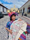 Cheerful mayan indian woman wearing a traditional huipil sells handcraft weavings in the city of Antigua in Guatemala Royalty Free Stock Photo