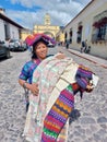 Cheerful mayan indian woman wearing a traditional huipil sells handcraft weavings in the city of Antigua in Guatemala Royalty Free Stock Photo