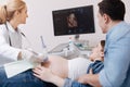 Cheerful medic providing ultrasound scanning of pregnant belly at work