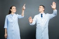 Cheerful medical coworkers touching invisible screen