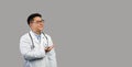 Cheerful middle aged chinese male therapist in white coat and glasses points to free space