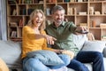 Cheerful middle aged couple having fun while watching tv at home together Royalty Free Stock Photo